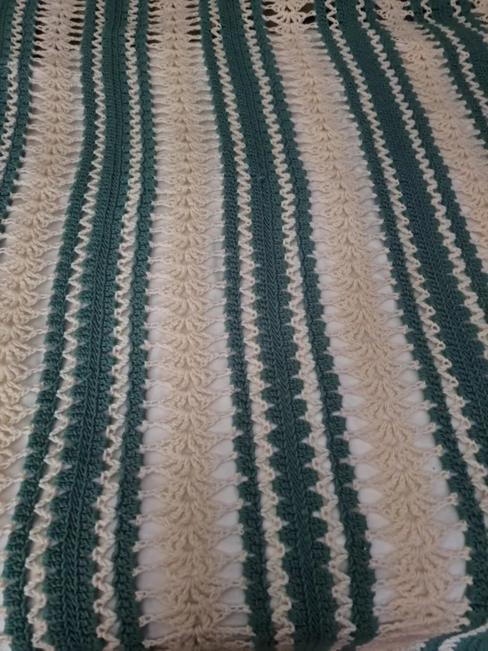 Handmade crochet blanket features a striped pattern in teal and cream. This item
